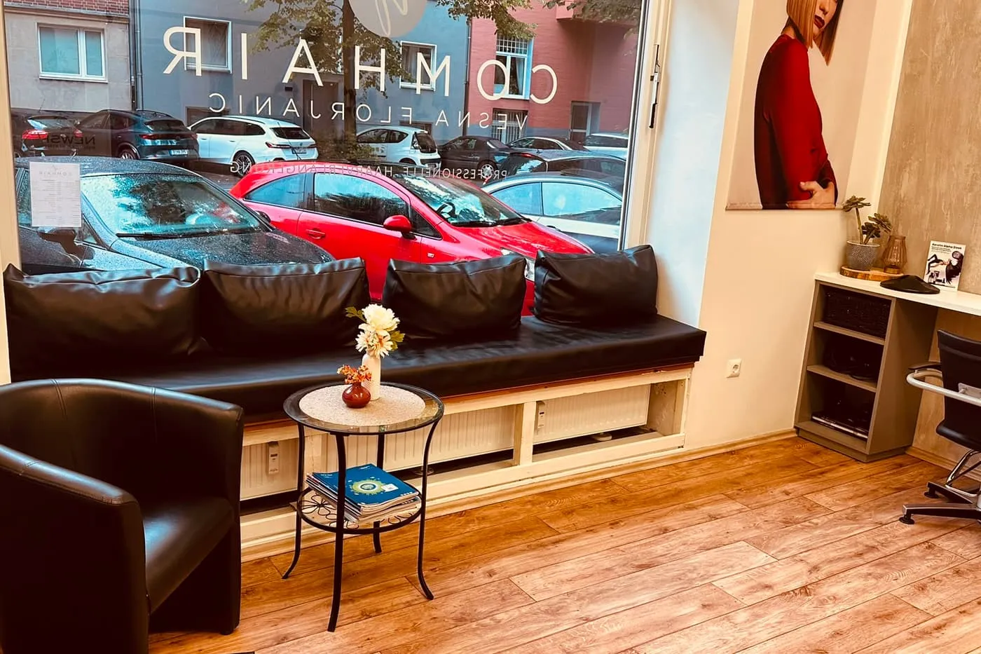 Schaufenster des Salons Comhair von innen, mit Schriftzug im Glas und Blick auf die Merowingerstraße