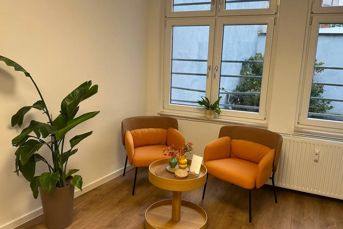 Wartebereich mit zwei Sesseln, Tisch und Pflanze am Fenster im Salon Comhair